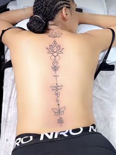 a woman laying in bed with her back turned to the camera and tattoos on her lower back