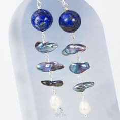 Add a touch of elegance to your jewelry collection with these stunning Lapis Lazuli and freshwater pearl drop earrings. The design features a 12 mm natural Lapis Lazuli stone bead, accompanied by a chain of 3 blue pearls and a white freshwater baroque pearl at the end. Made with solid 925 sterling silver ear wires, wires, and eye pins, these earrings make a thoughtful and beautiful gift for your loved ones. Don't miss out on adding these unique and exquisite earrings to your collection! Material Baroque Pearl Dangle Earrings Set, Elegant Sterling Silver Pearl Earrings With Dangling Beads, Sterling Silver Pearl Drop Earrings With Dangling Beads, Sterling Silver Drop Earrings With Dangling Pearls, Elegant Pearl Earrings With Dangling Beads For Gift, Blue Pearl Charm Drop Earrings, Long Drop Pearl Earrings With Dangling Beads, Silver Pearl Earrings With Natural Stones, Elegant Blue Pearl Earrings With Natural Stones