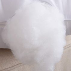 a white fluffy ball sitting on top of a bed