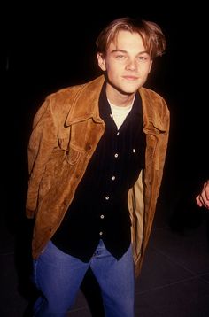 black and white photograph of a young man in leather jacket looking at the camera with one hand on his hip