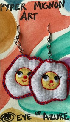 two embroidered earrings with faces on them