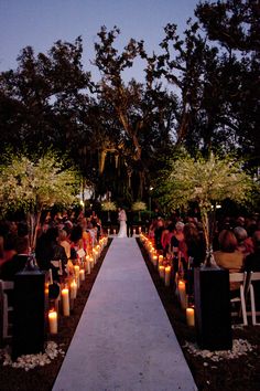 a wedding ceremony with candles lit in front of the aisle