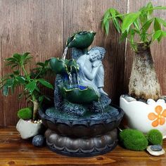 there is a small fountain with plants in it on top of a shelf next to a potted plant