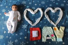 a baby laying on top of a bed next to two hearts