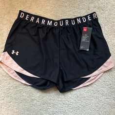 the under armour shorts are black and pink with white letters on them, along with a tag