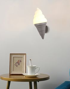 a coffee cup on a table next to a framed photograph and an ice cream cone hanging from the ceiling