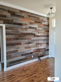 an empty room with wood planks on the wall and hard wood flooring in it