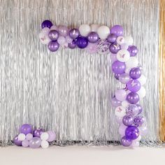 purple and white balloons are arranged in the shape of an o - letter on a silver backdrop