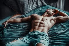 a shirtless man laying on top of a bed