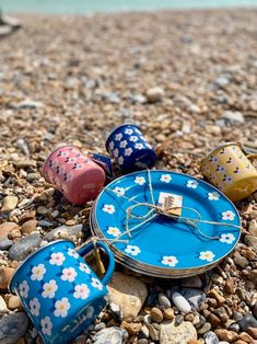 three tin canisters sitting on top of a rocky beach