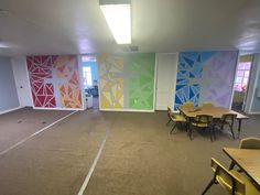 an empty room with tables and chairs in front of colorful wallpapers on the walls