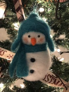 a snowman ornament hanging from a christmas tree in the shape of a penguin