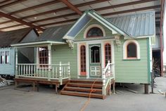 a small green house sitting in the middle of a building with stairs leading up to it