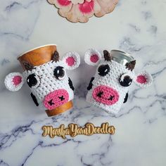 two crocheted cow mug cozyies sitting on top of a marble counter