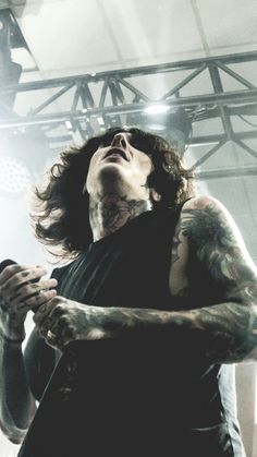 a man with long hair and tattoos holding a microphone