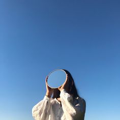 a woman holding a tennis racquet on top of a grass covered field under a blue sky