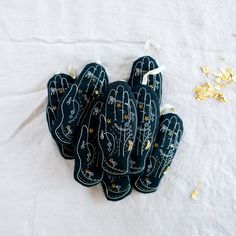 five black oven mitts with hand prints on them and gold flakes scattered around