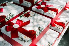 many red and white gift boxes with ribbons on them are lined up in rows together