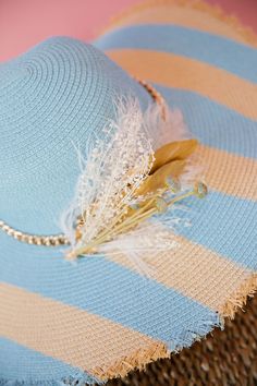 Ready to soak up some sun in style? Look no further than THE SOFIA SUN HAT! Made of durable straw, this floppy hat features playful baby blue painted stripes and a chic gold chain band. The elegant combo of cream and gold feathers and flowers adds a touch of whimsy to this must-have accessory. This hat is ONE OF A KIND, created by our owner Stephanie. To receive item quicker, expedited shipping is available at checkout. Beach Hats With Feathers And Wide Brim, Wide Brim Beach Hat With Feathers, Chic Gold Summer Hat, Chic Gold Beach Hat, Chic Gold Fedora Straw Hat, Summer Hat With Feather Trim, Chic Feathered Hats For Spring, Chic Spring Hats With Feathers, Chic Spring Hat With Feathers