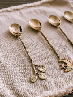 five spoons are lined up next to each other on a cloth with gold colored handles