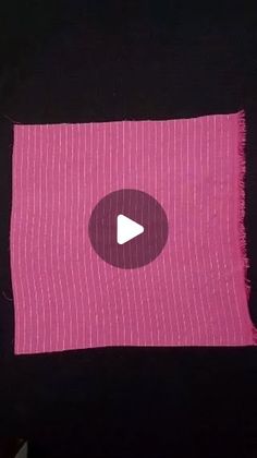 a pink piece of cloth with a white button in the center and a black background