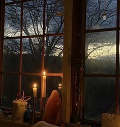 a candle is lit in front of a window with the view of trees outside at night