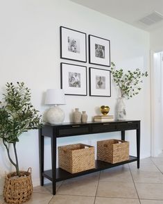 there is a black table with baskets on it and three pictures above the table in front of it