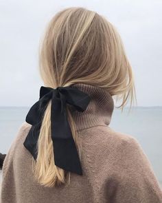 a woman with long blonde hair wearing a black bow