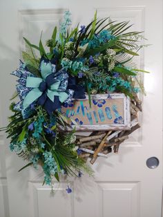 a wreath on the front door with blue and white flowers, leaves and branches around it