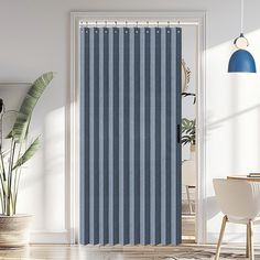 a blue and white vertical blind in a room with a chair, potted plant and lamp