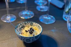 a bowl filled with food sitting on top of a table next to some wine glasses