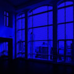 an empty room with large windows and city skyline seen through the blue tinted window panes