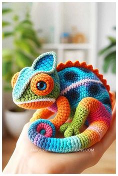 a small crocheted chamelon is sitting on someone's hand