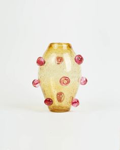 a yellow vase sitting on top of a white table next to a red and pink object