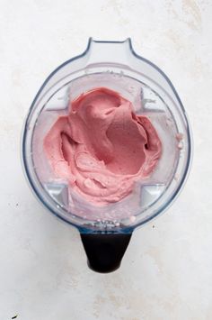 a blender filled with pink food on top of a table