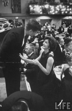 black and white photograph of people in formal wear talking to each other at an event