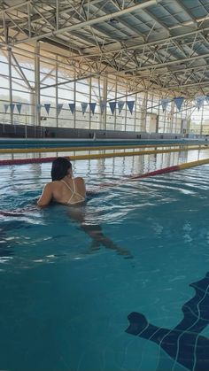 a woman in a swimming pool with her back to the camera