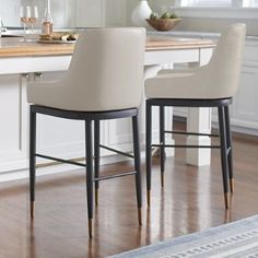 two white chairs sitting in front of a counter top with a vase on the table