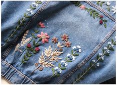 an embroidered jean jacket with flowers and leaves on it