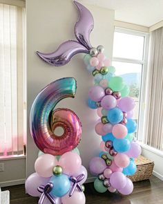 the balloon arch is decorated with mermaid tail balloons and an underbelly number six