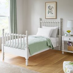 a white bed sitting in a bedroom next to a window with green drapes on the windowsill