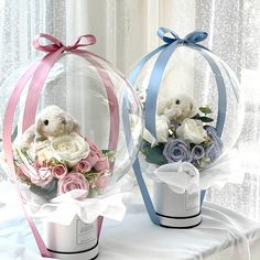 two clear vases with flowers and teddy bears in them on a white table cloth