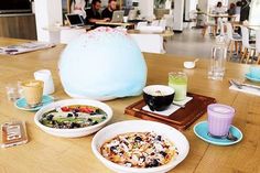 a wooden table topped with plates and bowls of food