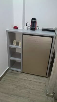 a small kitchen with a metallic refrigerator freezer next to an open shelf on the wall