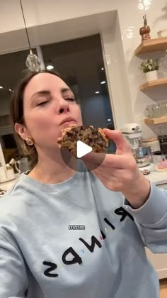 a woman is eating a cookie in the kitchen