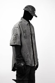 The Distressed Spliced Denim Half-Shirt redefines urban craftsmanship with its unique design and rugged aesthetic. This piece features zipper pockets on the chest and sleeves, adding a functional edge to its streetwear appeal. The shirt has undergone a washing process for a distressed, vintage look that embodies an effortless cool. Arc-shaped splicing and a curved hemline enhance its distinctive style, while the short sleeves make it ideal for layering or wearing alone in warmer weather. Crafted Urban Style Washed Black Denim Jacket For Streetwear, Urban Denim Jacket For Outdoors, Denim Tops With Pockets For Streetwear, Urban Washed Denim Jacket, Edgy Streetwear Tops With Pockets, Edgy Tops With Pockets For Streetwear, Rugged Aesthetic, Half Shirt, Half Shirts