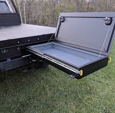 an open truck bed sitting on top of a lush green field