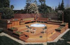 a wooden deck with chairs around it and a hot tub in the middle surrounded by plants