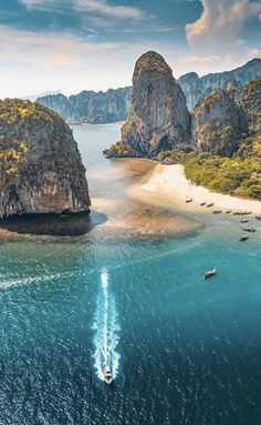 an aerial view of boats in the water near large rock formations and beached islands