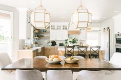 a dining room table with chairs and bowls of fruit on it in front of an oven